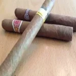 Three cigars laying on top of each other on a wooden table