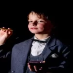 little boy holding a faux cigar