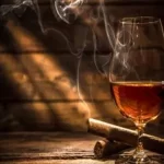 smoking cigar and a glass of wine next to it