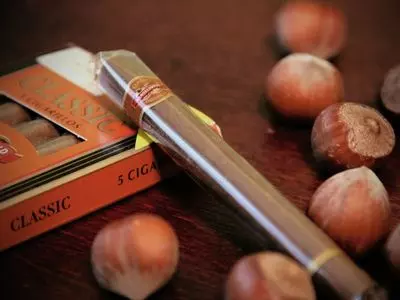 Cigar and cigar pack next to loose nuts