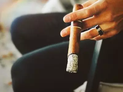 Person holding a cigar with a longer ash
