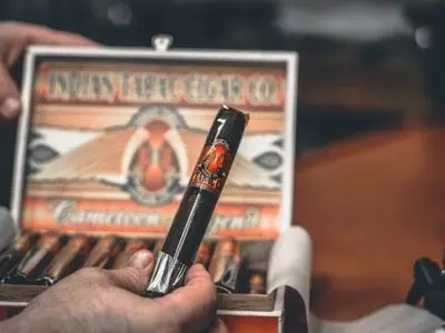 Person holding a cigar with an open cigar box