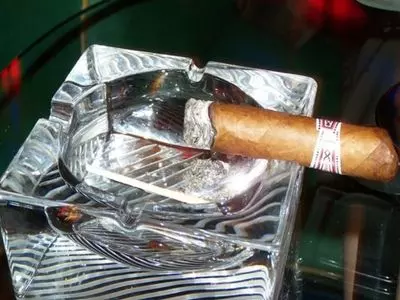 A smoked cigar sitting inside of a glass ashtray