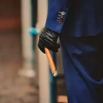Person holding a cigar at their side